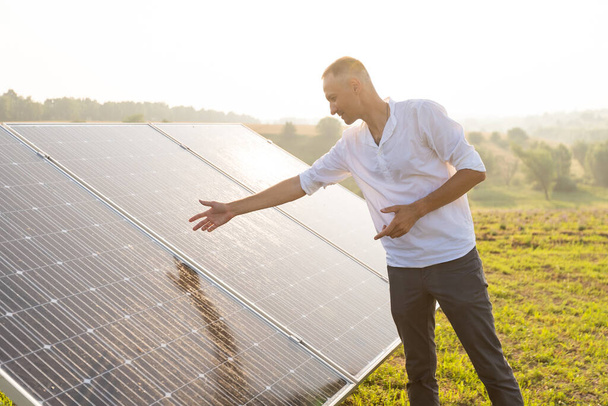 ung inženýr kontroluje fungování slunce a čistotu fotovoltaických solárních panelů při západu slunce. Koncepce: obnovitelná energie, technologie, elektřina, služby, zelená, budoucnost - Fotografie, Obrázek