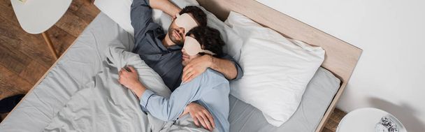 πάνω όψη του gay ζευγαριού με μάσκες ματιών που κοιμάται στο κρεβάτι, πανό - Φωτογραφία, εικόνα