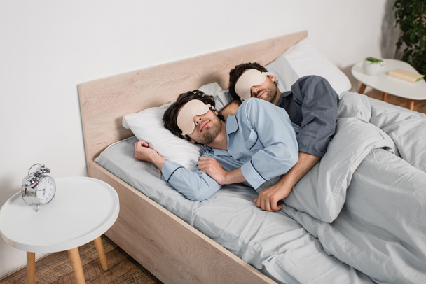 gay couple in eye masks hugging while sleeping in bed - Photo, Image
