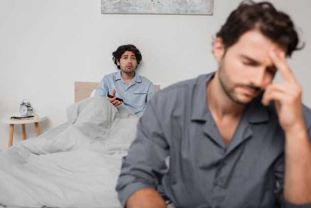 sconvolto uomo tenendo smartphone e guardando stanco fidanzato in primo piano offuscata  - Foto, immagini