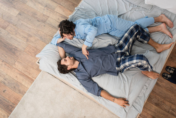 top view of young gay couple in pajamas resting on bed - Photo, Image