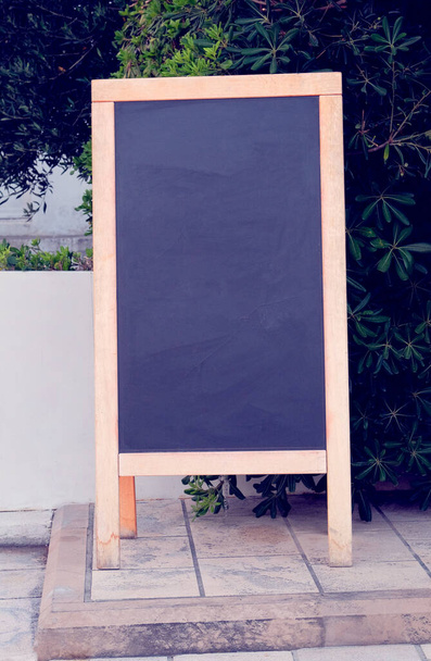 Zwart bord menu zwarte kleur voor tekst, bericht of reclame. Mockup staat vlakbij het restaurant aan de zeekust. Zonnige dag. - Foto, afbeelding