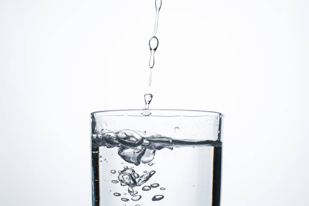 Джет води або алкоголю вливається в склянку з бризками і бульбашками, копіює простір
. - Фото, зображення