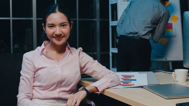 Portrait of beautiful executive businesswoman smart casual wear looking at camera and smiling, happy in modern office workplace night. Young Asia lady talk to colleague in video call meeting at home. - Photo, Image