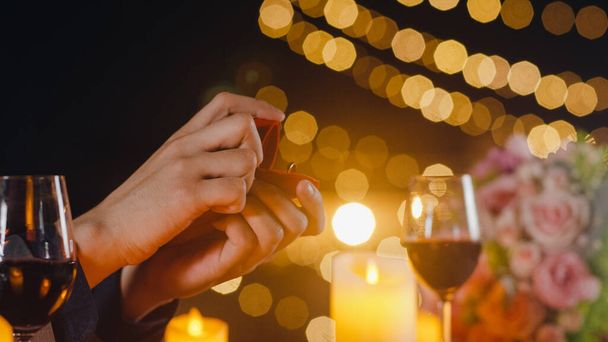 Młody azjata poprosić dziewczyny do małżeństwa w romantycznej kolacji picia wina w restauracji na dachu w nocy miasta z szczęśliwy moment świętować rocznicę. Relacje miłosne, świętowanie koncepcji małżeństwa. - Zdjęcie, obraz