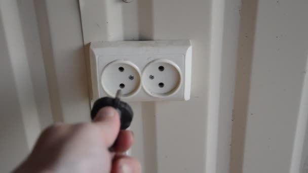 A man inserts a plug into an electrical outlet - Footage, Video