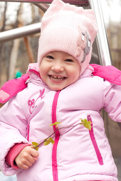 Ein süßes kleines Mädchen in Jacke und Hut mit Lähmung sitzt im Kinderwagen. Behinderungen. Spaziergänge im Freien - Foto, Bild