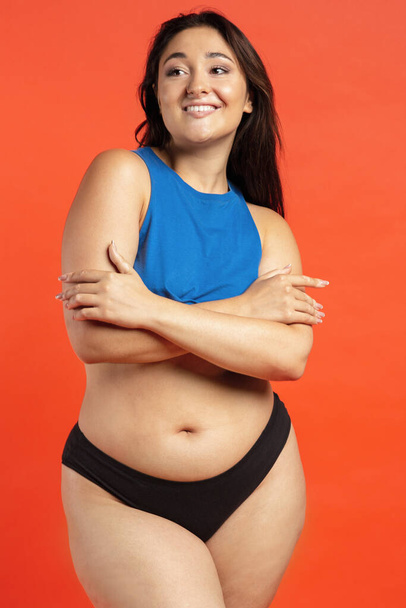 Young beautiful plump woman in cotton underwear on orange background - Photo, Image