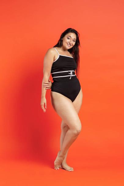Young beautiful plump woman in black underwear on orange background - Photo, Image