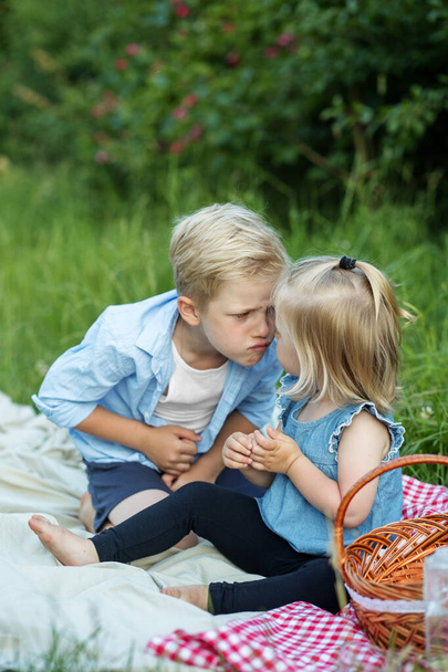 Outdoor picnic. Funny happy baby. Brother and sister are sitting in nature, having fun. - Zdjęcie, obraz