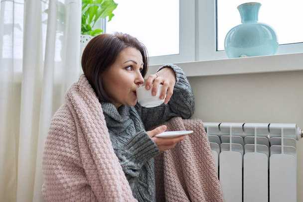Winter season, woman warming up near home heating radiator - Photo, Image