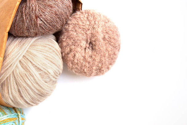Bolas de hilo de lana de diferentes colores y agujas de punto en una bolsa ecológica artesanal sobre un fondo blanco. Ropa de lana hecha a mano. Pasatiempo tradicional. Copiar espacio - Foto, Imagen