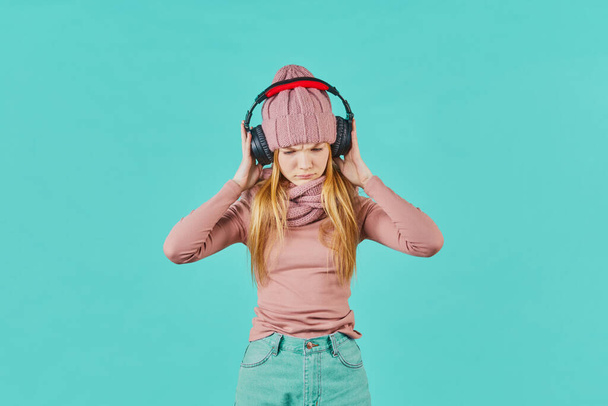 Beautiful young woman listening to music using headphones. sad expression. - Photo, Image