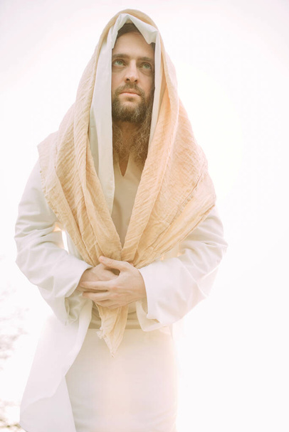 Jézus Krisztus a hagyományos fehér köntösébe öltözve állt az ég hátterében. Elszigetelt kép. - Fotó, kép