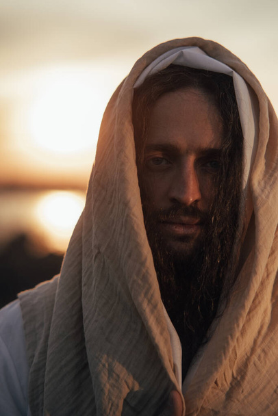 Porträt von Jesus Christus in seinem traditionellen weißen Gewand vor dem Hintergrund des Sonnenuntergangs. - Foto, Bild