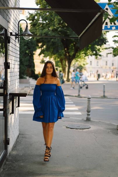 Portrait happy young woman wearing blue dress laughing looking at camera standing on street. Urban background - Φωτογραφία, εικόνα