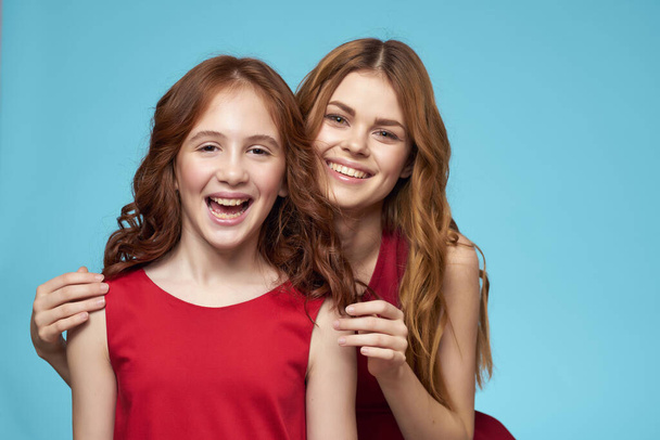 αστεία μαμά και κόρη διασκέδαση κόκκινα φορέματα μόδα μπλε φόντο - Φωτογραφία, εικόνα