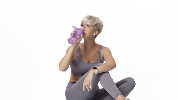 Sports girl drinks water while sitting and looking at the camera.COPY SPACE - Foto, immagini