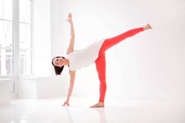 Jeune femme mince en tenue de sport effectuant la pose de yoga, isolé sur fond de studio blanc. Style de vie sain, sport et concept de fitness - Photo, image