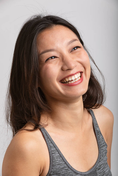 Portrait beautiful Asian girl with big smile and brown hair. Sportswear and lipstick. White background - Foto, imagen