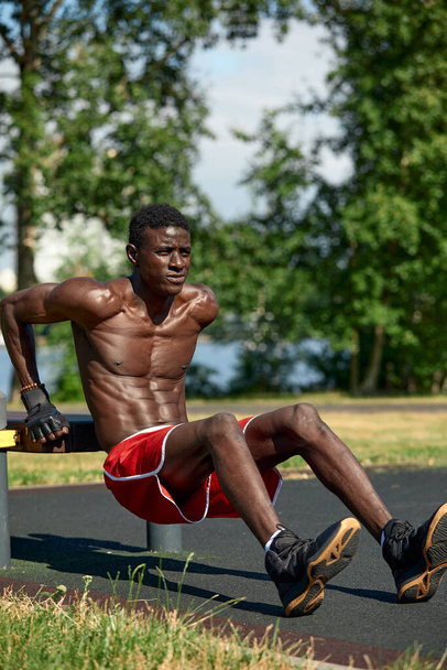 Sportovec dělá kliky na sportovním hřišti, atlet Afroameričan dělá kliky na outdoorové tělocvičně, sportovní životní styl, usiluje o úspěch - Fotografie, Obrázek