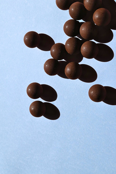 Тёмные шоколадные конфеты с сильным пастельно-голубым фоном - Фото, изображение