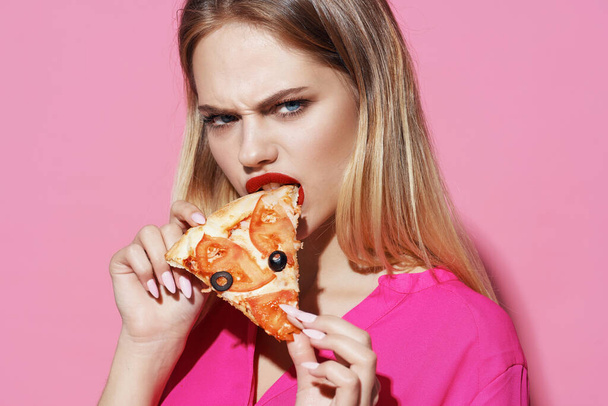 rubia comer pizza comida rápida rosa fondo - Foto, Imagen