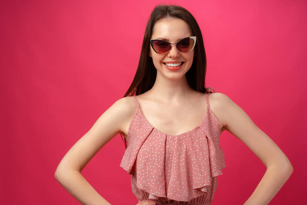 Young casual brunette woman in sunglasses against pink background - Foto, immagini