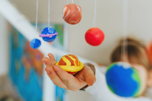 Mała dziewczynka bawiąca się planetami zabawki wykonane przez siebie z kolorowych formowanie gliny wewnątrz - Zdjęcie, obraz