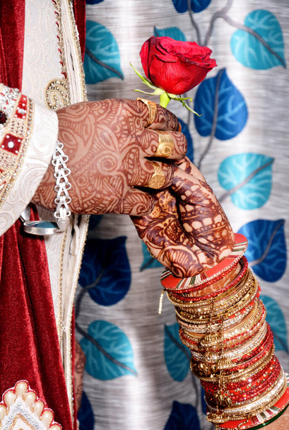 A closeup of an Indian groom giving a rose flower to a bride during wedding ceremony - Фото, изображение