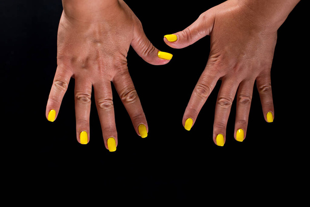 Finger nails with yellow manicure close up isolated on black background. - Photo, Image