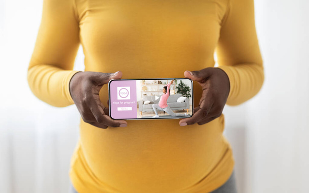 Genç siyah wonan hamilelik sırasında yoga için mobil uygulama kullanıyor - Fotoğraf, Görsel