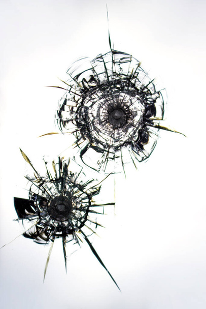 Cracks sul vetro da colpi di pistola. Una vetrina rotta dopo una rapina. Cracks texture per il design, nero su sfondo bianco. - Foto, immagini