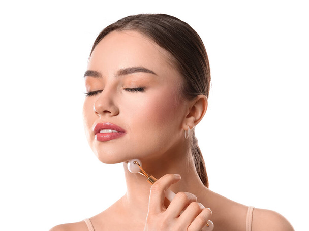Beautiful young woman with facial massage tool on white background - Photo, Image
