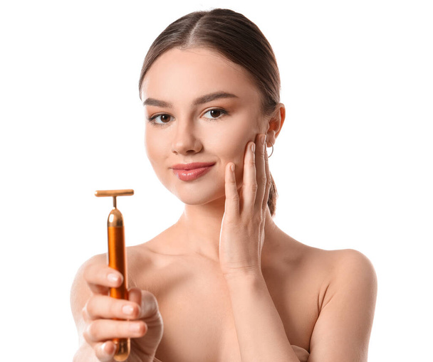 Mulher bonita com ferramenta de massagem facial no fundo branco - Foto, Imagem