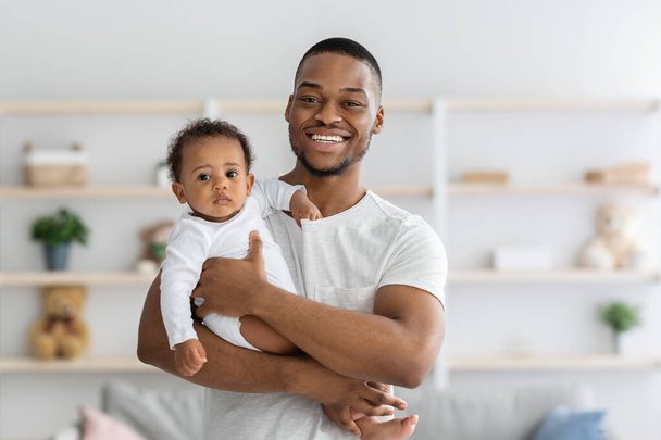 Paternidad. retrato de feliz joven negro hombre sosteniendo su adorable bebé - Foto, imagen