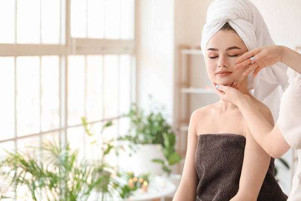Mujer joven recibiendo masaje facial en salón de belleza - Foto, imagen