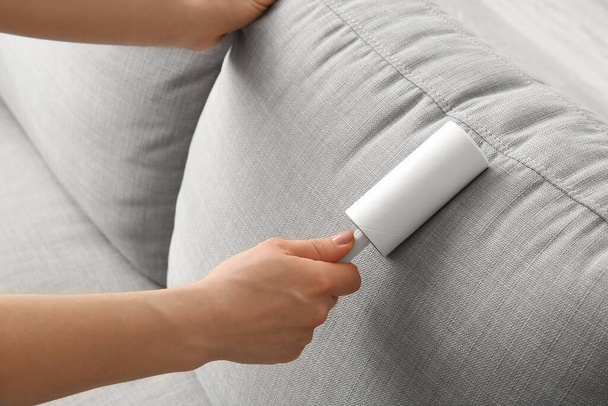 Woman cleaning sofa with lint roller, closeup - Photo, Image