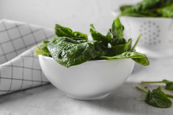Bowl with fresh spinach leaves on light background, closeup - Фото, изображение