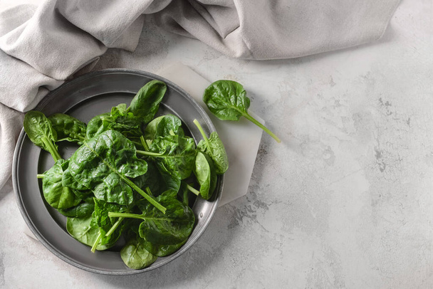 Plate with fresh spinach leaves on light background - Photo, Image