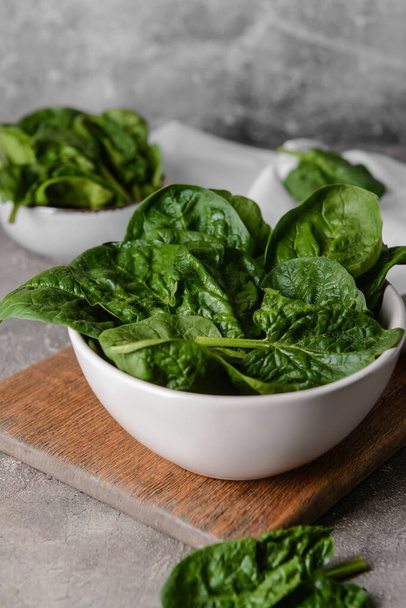 Bowl with fresh spinach leaves on grunge background - Photo, Image