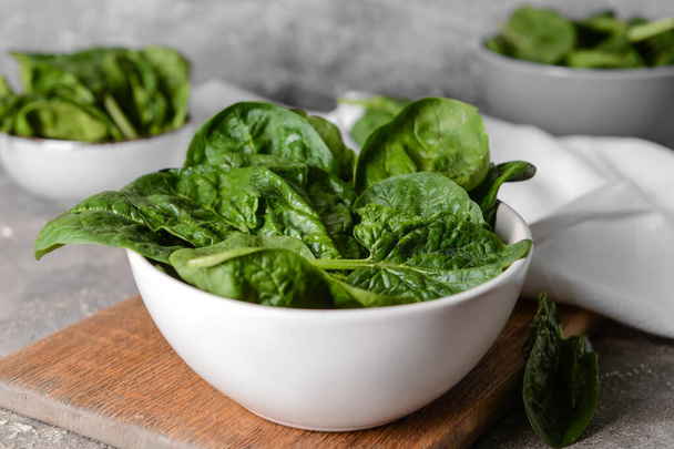 Bowl with fresh spinach leaves on grunge background, closeup - Foto, afbeelding