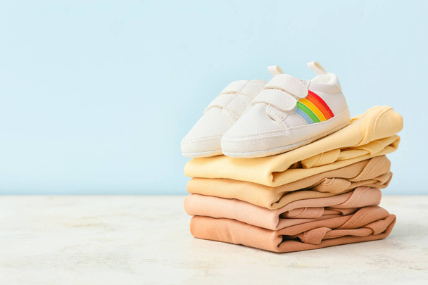 Stack of baby clothes and shoes on color background - Photo, Image