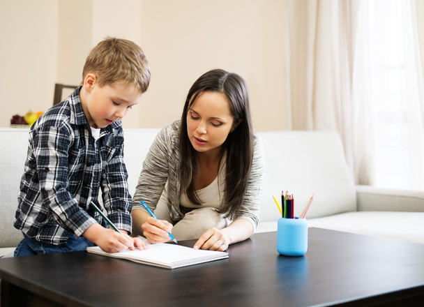 Happy young mother with her son drawing in home interior  - Foto, imagen