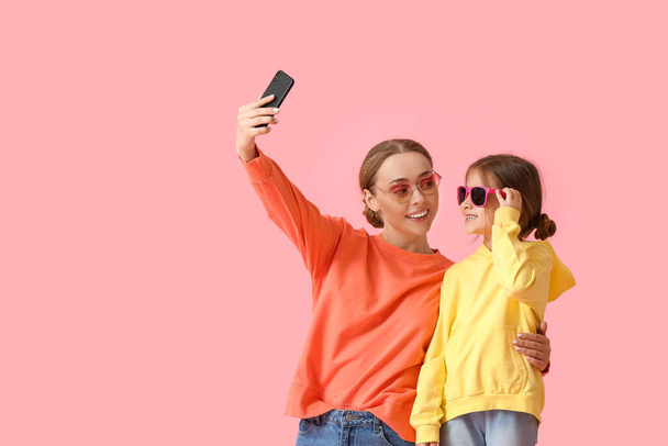 Young woman and her little daughter taking selfie on color background - Foto, immagini