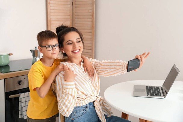 Joven mujer y su pequeño hijo tomando selfie en casa - Foto, imagen
