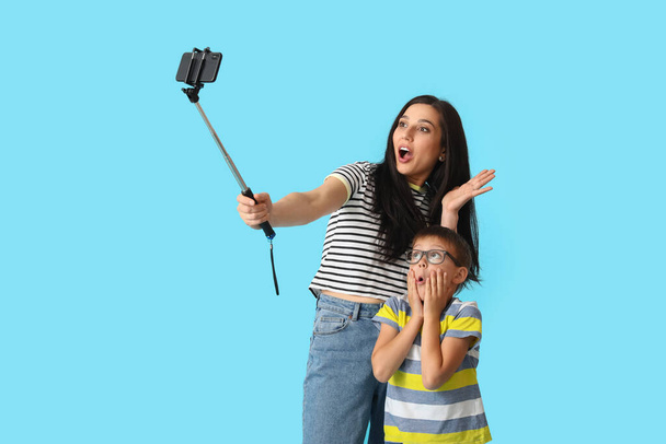 Junge Frau und ihr kleiner Sohn machen Selfie auf farbigem Hintergrund - Foto, Bild