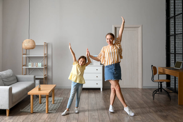 Nuori nainen ja hänen pieni tyttärensä tanssivat kotona - Valokuva, kuva