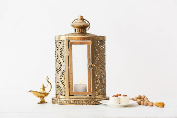 Мусульманський ліхтар з лампою Аладдіна, тасбійським та турецьким цукерками на світлому тлі. - Фото, зображення