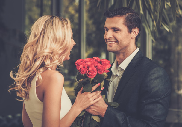Bonito homem com um monte de rosas vermelhas namoro sua senhora
 - Foto, Imagem